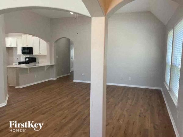A kitchen area with wooden floors and a refrigerator.