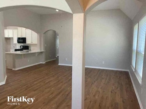A kitchen area with wooden floors and a refrigerator.