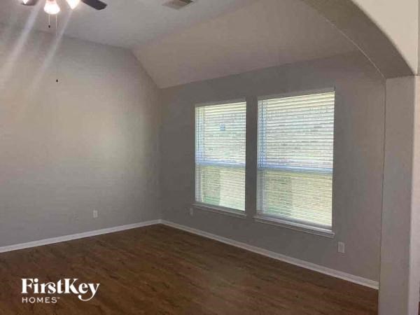 A room with wooden floors and a window with blinds.