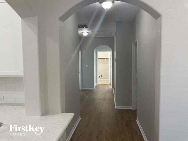 A long hallway with arched doorways and wood floors.