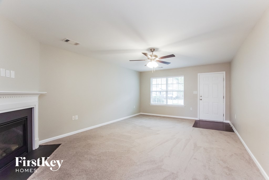 A spacious room with a fireplace and a ceiling fan.