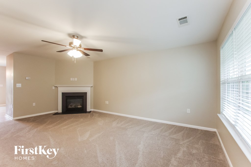 A spacious living room with a fireplace and a ceiling fan.