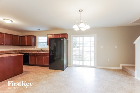 A kitchen with brown cabinets and a black refrigerator.