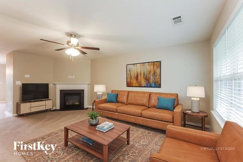 A living room with a brown couch and a painting on the wall.