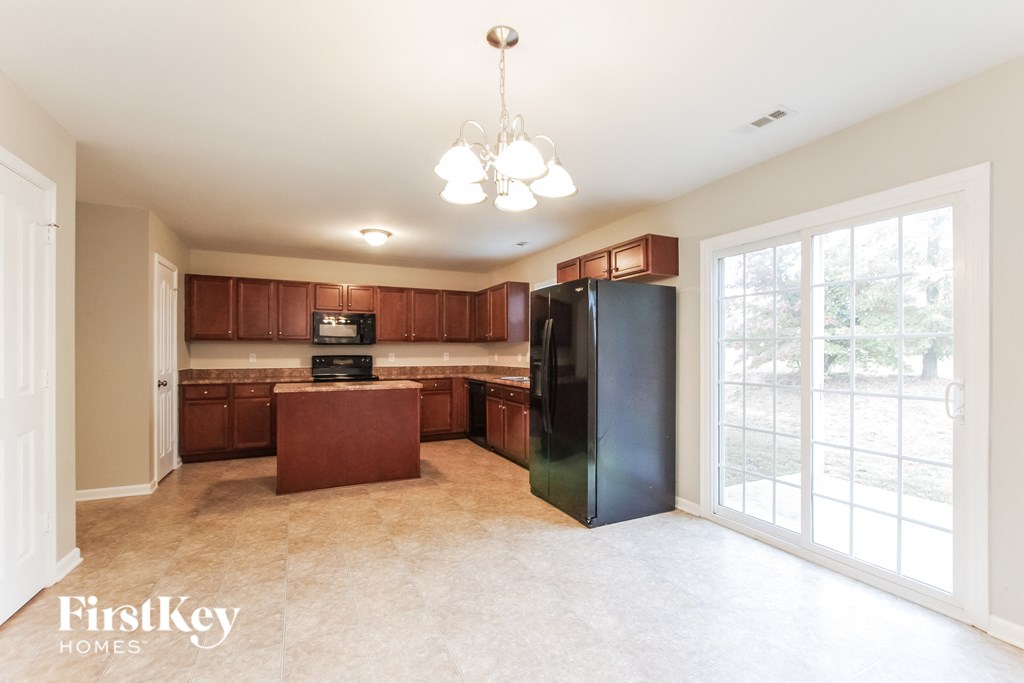 A kitchen with brown cabinets and a black refrigerator.