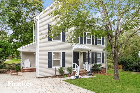 a white house with black shutters and a tree