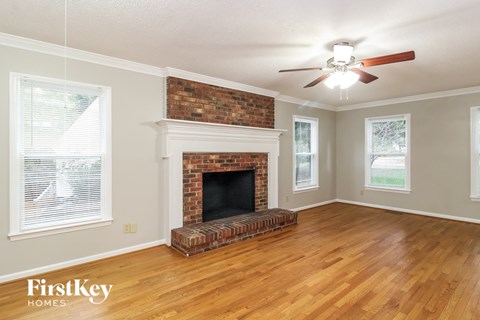 the living room of a house with a brick fireplace and wooden floors