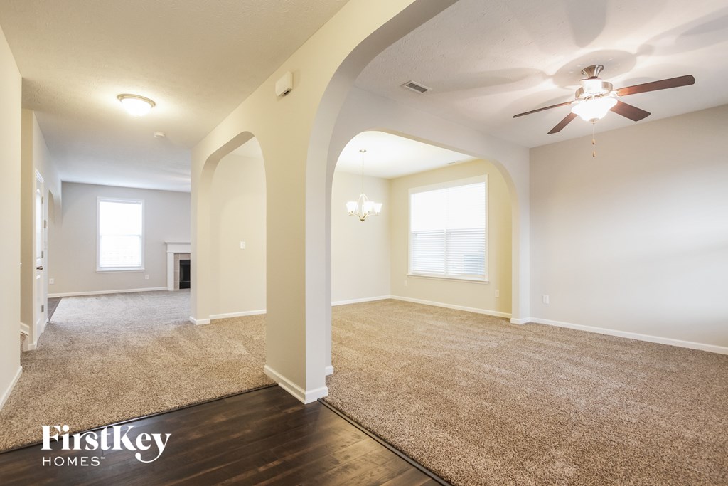 A spacious room with a carpeted floor and a ceiling fan.
