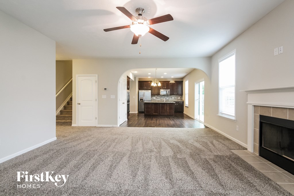A spacious living room with a fireplace and a ceiling fan.