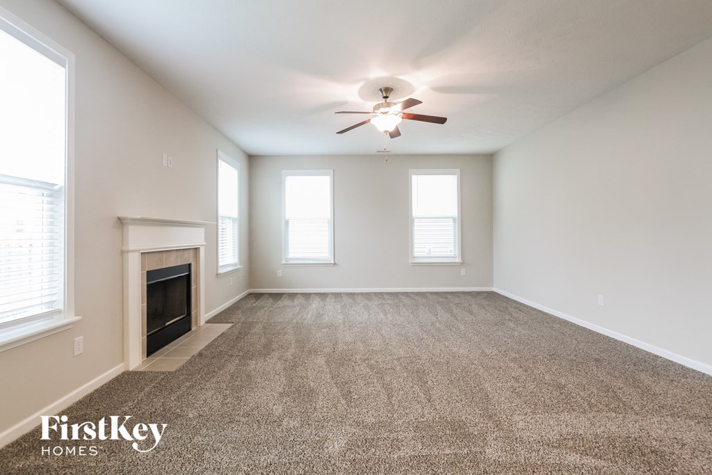 A spacious room with a fireplace and a ceiling fan.
