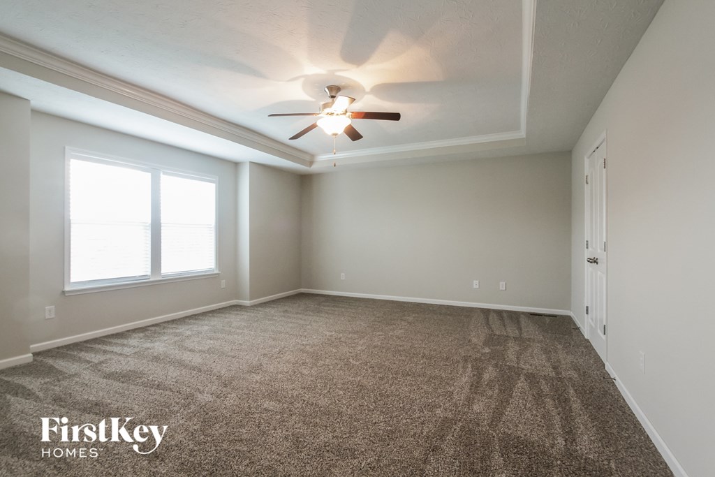 A spacious room with a carpeted floor and a ceiling fan.