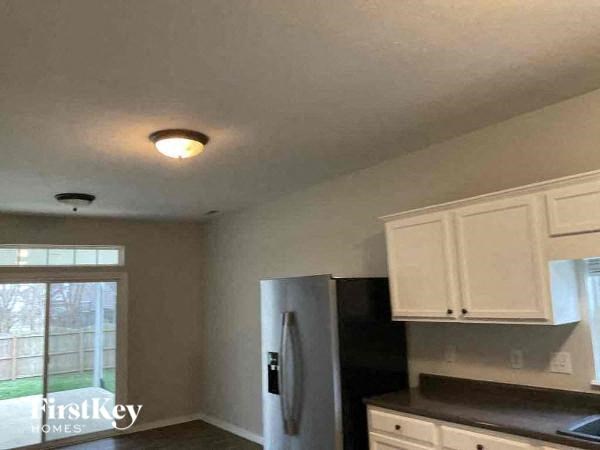 A kitchen with a refrigerator, cabinets, and a window.