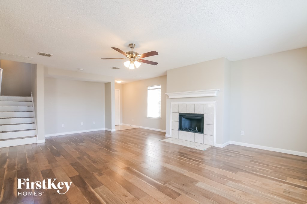 A spacious living room with a fireplace and wooden floors.