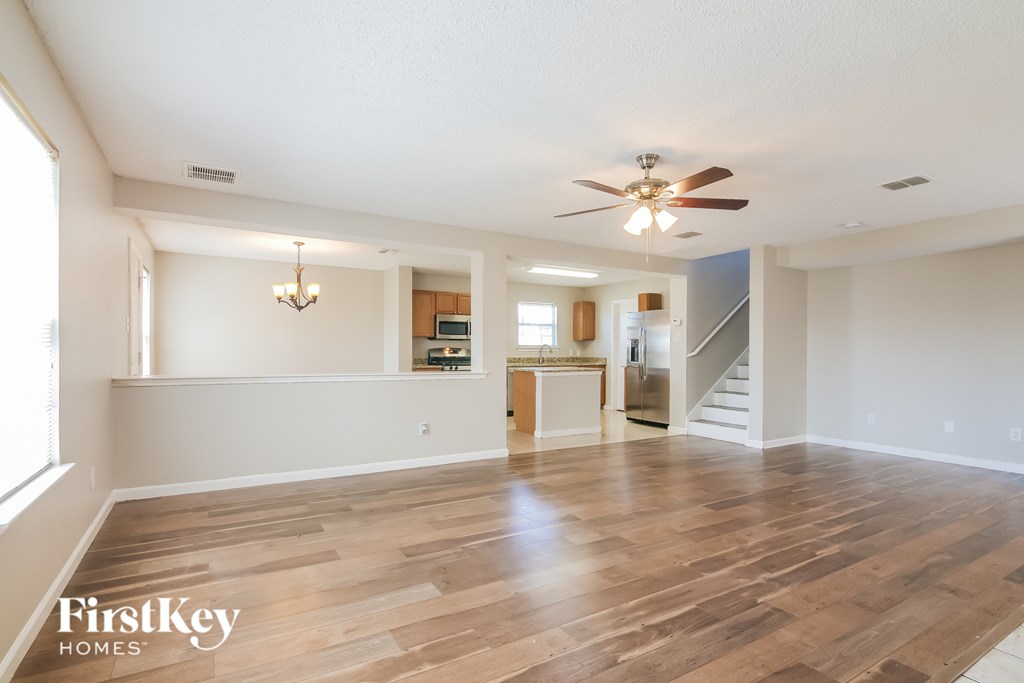 A spacious living room with wooden flooring and a ceiling fan.