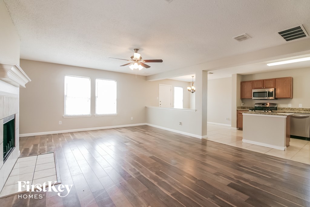A spacious living room with wood flooring and a fireplace.