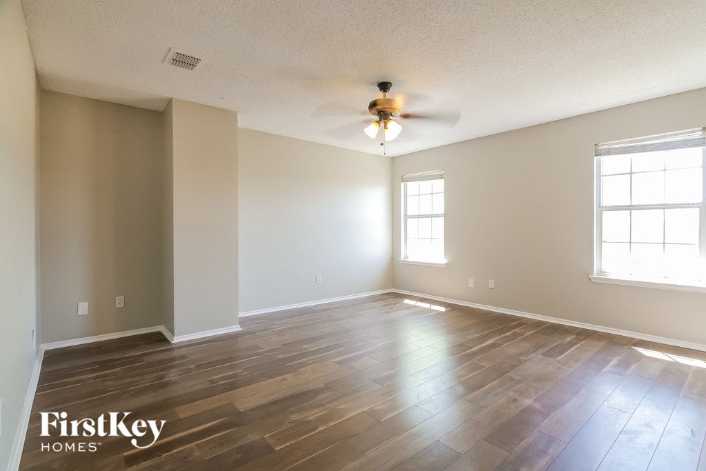 A spacious room with wooden flooring and a ceiling fan.