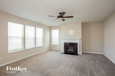 A spacious living room with a fireplace and a ceiling fan.