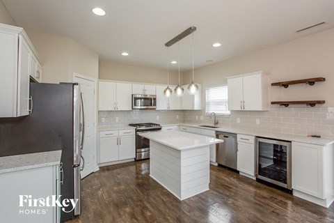 A kitchen with white cabinets and a wooden floor.