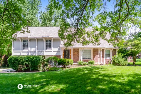 a white and brick house with green grass and trees