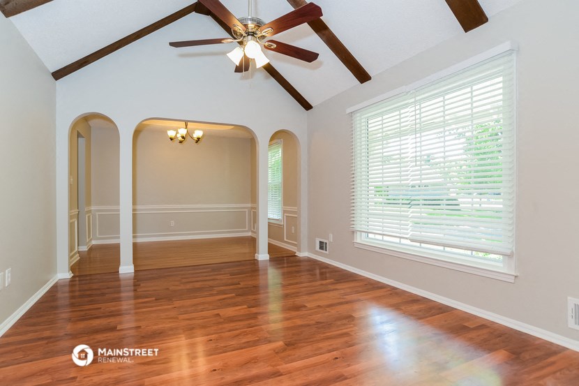 an empty living room with a ceiling fan and a large window