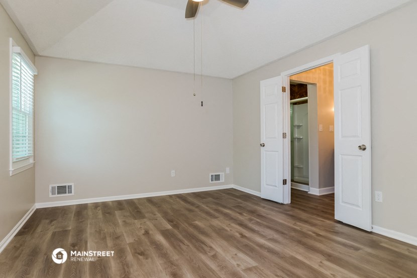 the spacious living room with wood flooring and white walls