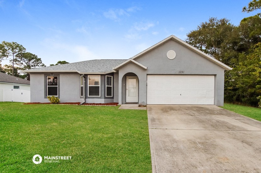 a gray house with a white garage door and a lawn