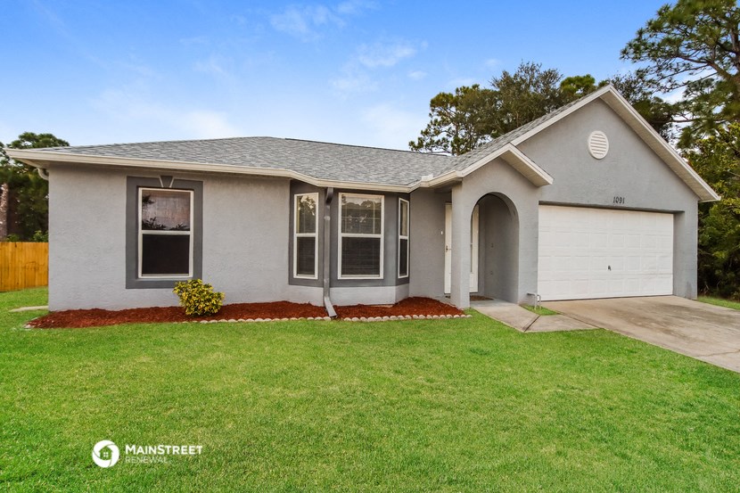 a gray house with a lawn and a white garage door