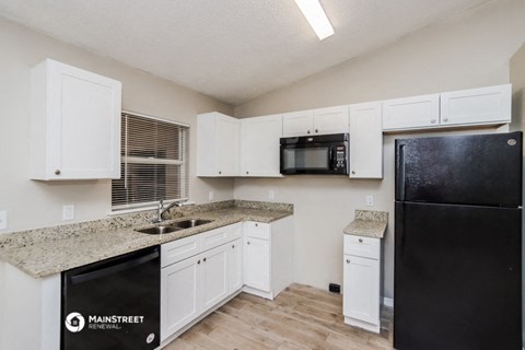 a kitchen with white cabinets and a black refrigerator