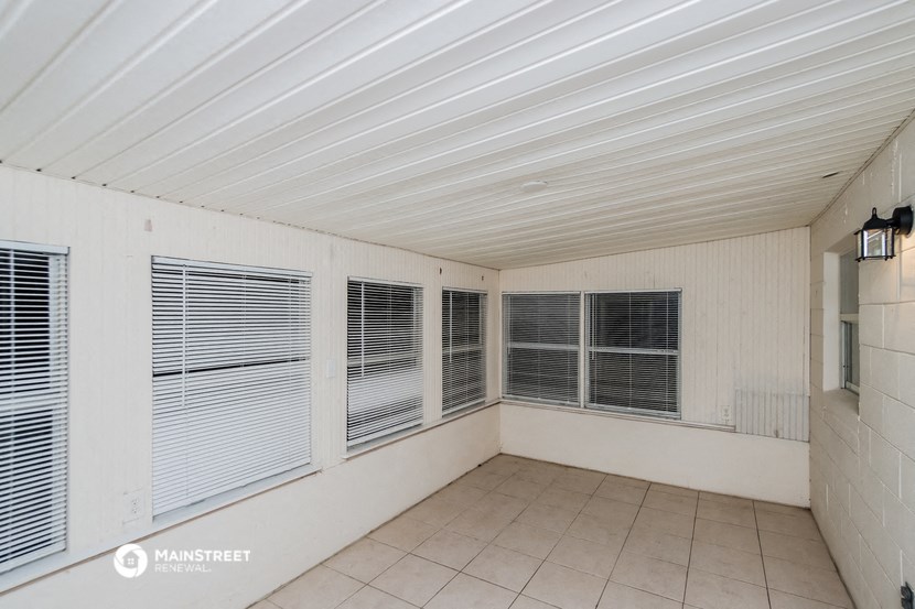 an empty living room with windows and a tiled floor