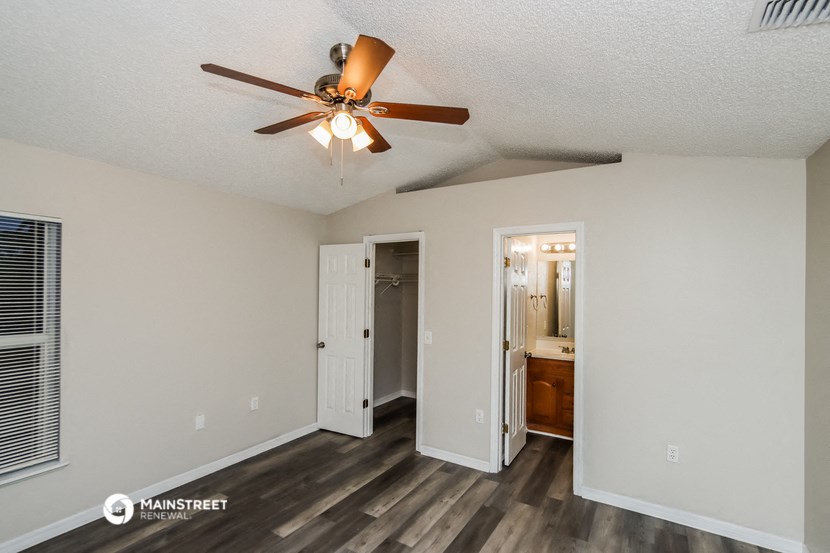a living room with a ceiling fan and a door to a bathroom
