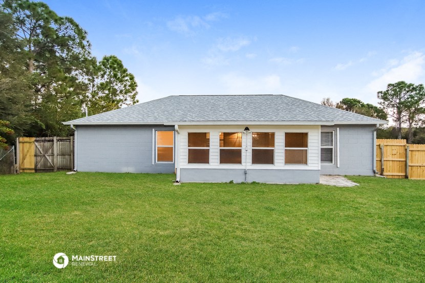 a small white house with a lawn and a fence