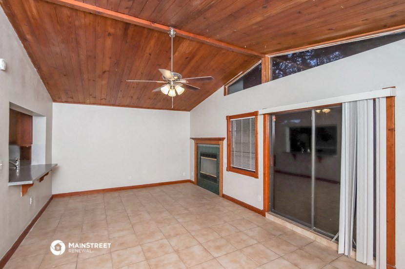 an empty living room with a ceiling fan and a sliding glass door