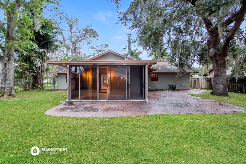 a backyard with a house with a patio and a tree