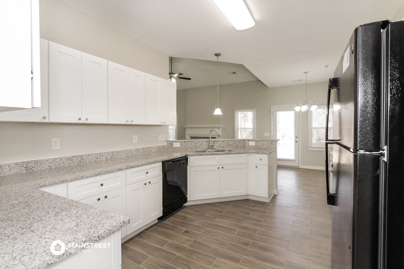 a large kitchen with white cabinets and a wood floor