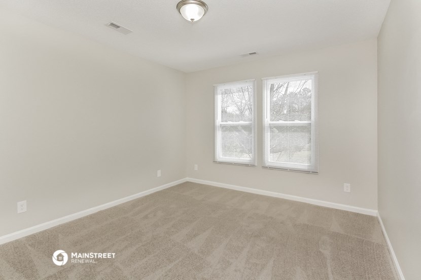 the spacious living room with carpeting and two windows
