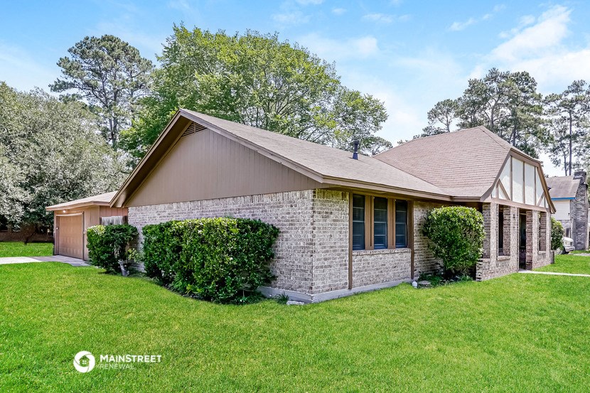 a small brick house with a green lawn and trees