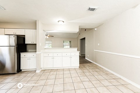 a large kitchen with white cabinets and a stainless steel refrigerator
