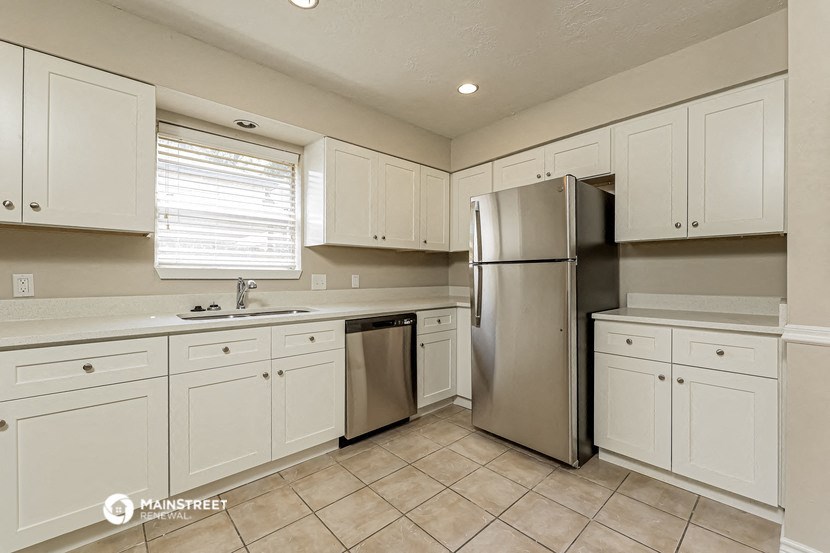 a kitchen with white cabinets and a stainless steel refrigerator