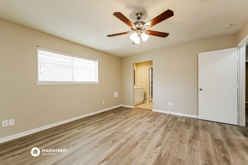the spacious living room with hardwood floors and a ceiling fan