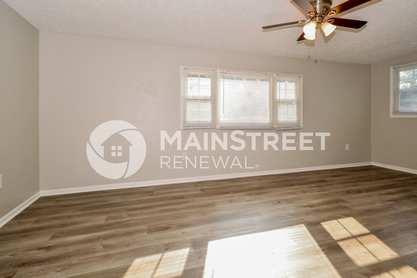 an empty living room with a ceiling fan and a window