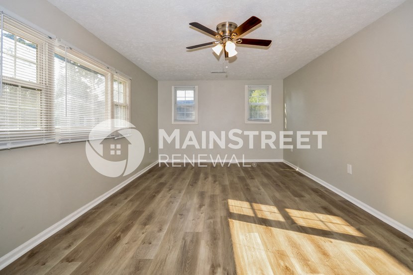 a spacious living room with hardwood flooring and a ceiling fan
