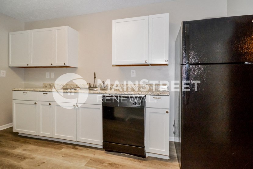 a kitchen with white cabinets and a black refrigerator