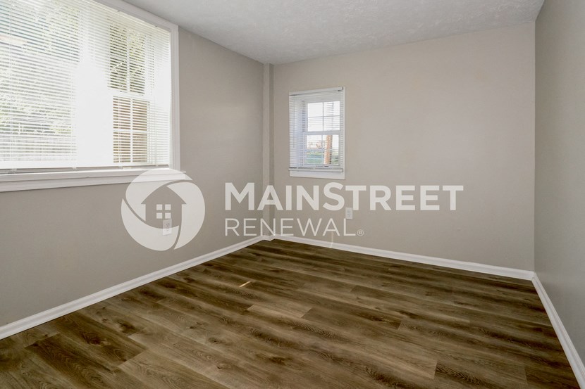 a bedroom with a hardwood floor and a window