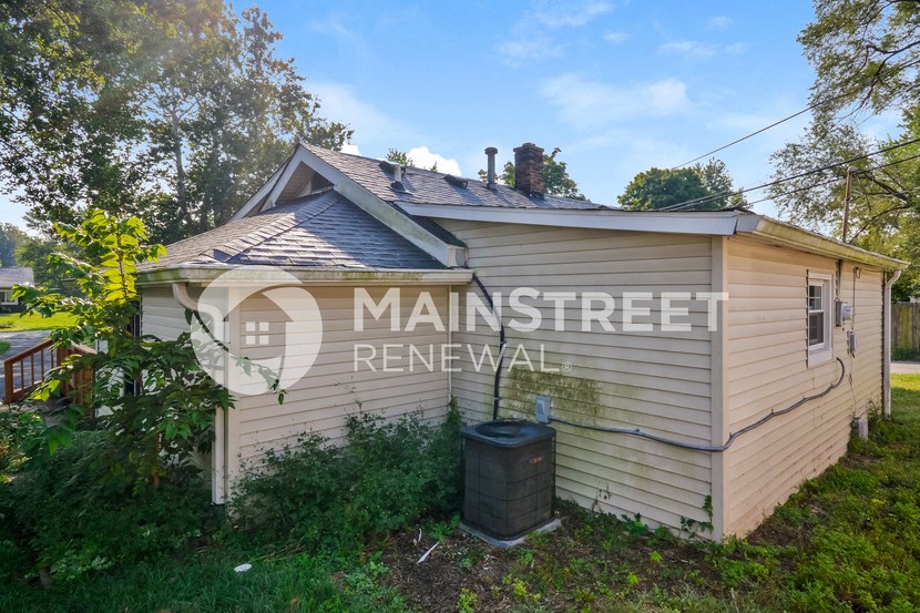 a small house with a trash can in front of it