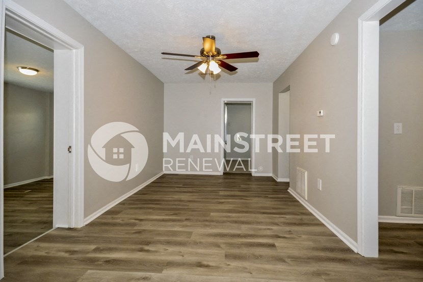 a renovated living room with hardwood floors and a ceiling fan