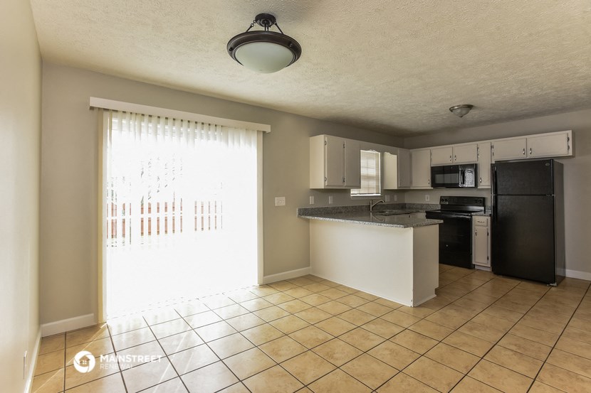 a kitchen with an island and a black refrigerator and a sink