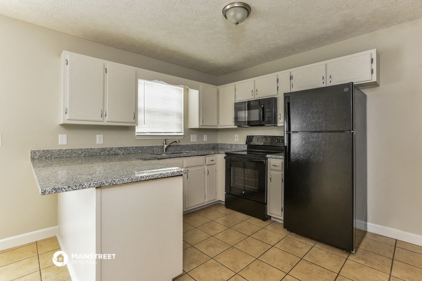 a kitchen with a granite counter top and a black refrigerator