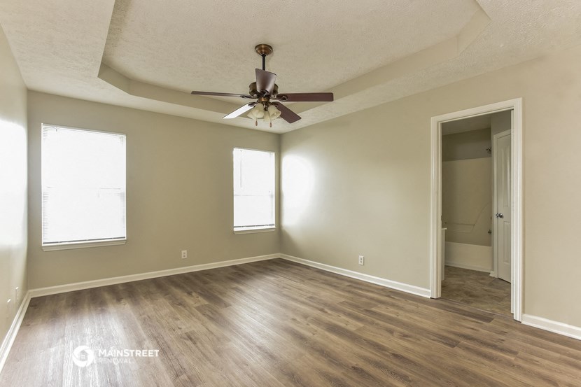 the spacious living room of an empty house with a ceiling fan