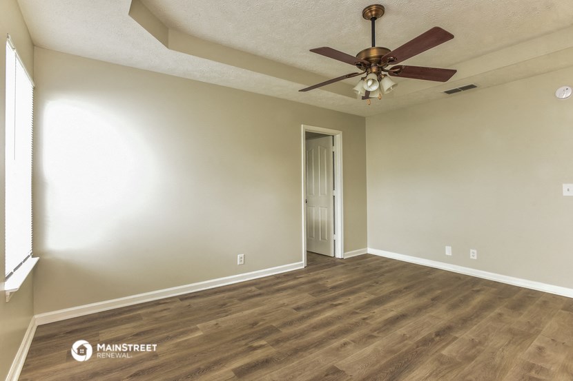 an empty living room with wooden floors and a ceiling fan
