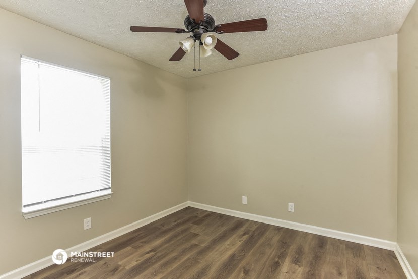 an empty room with a ceiling fan and a window
